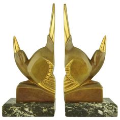 a pair of golden bird bookends on marble bases