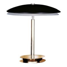 a table lamp with a black shade on it's base and a gold plate underneath