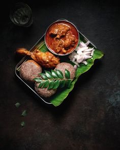 some food is sitting on a plate with green leaves and onions next to the bowl