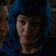 two people with blue hair are looking at each other and one is staring into the camera