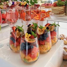 there are many glasses with fruit in them on the table next to other desserts