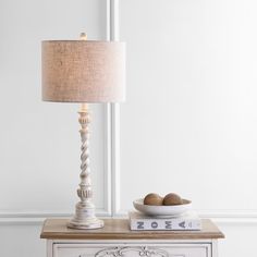 a lamp on top of a dresser next to a bowl