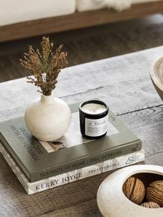 a table topped with two books and a vase filled with flowers on top of it