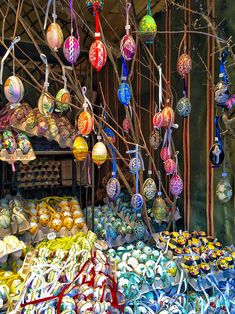 there are many different colored ornaments hanging from the branches in this market place, including eggs and hams