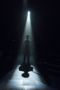 a man standing in the middle of a dark room with light coming from behind him