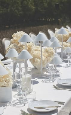 the table is set with white linens and place settings for an elegant dinner party