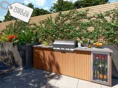 an outdoor kitchen with grill, refrigerator and wine bottles on the outside wall next to a wooden fence