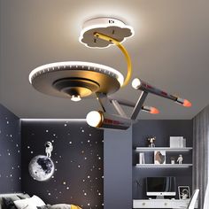 a child's bedroom with space themed lighting and decor on the ceiling, along with a bed