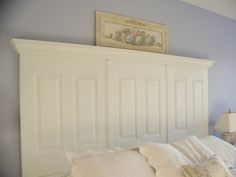 a white bed sitting in a bedroom next to a lamp on a dresser and window