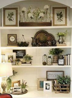 a white book shelf filled with lots of books and flowers on top of it's shelves