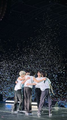 group of people hugging on stage with confetti in the background