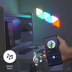 a hand holding an iphone with music notes coming out of the screen next to a computer