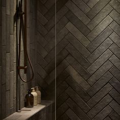 a walk in shower sitting next to a tiled wall and shelf with bottles on it