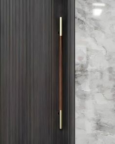 a bathroom door with a wooden handle on the side and white marble walls behind it