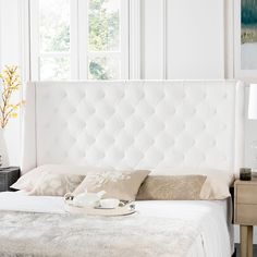 a white bed sitting in a bedroom next to a window