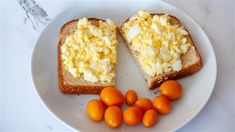 two pieces of toast with eggs and oranges on a plate