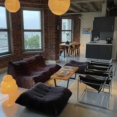 a living room filled with lots of furniture and lights hanging from the ceiling above it