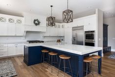 a large kitchen with white cabinets and blue island