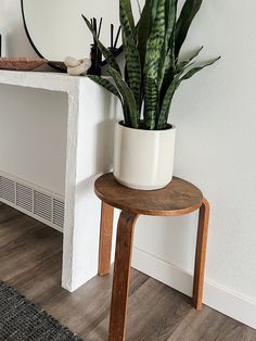 a white potted plant sitting on top of a wooden table next to a mirror