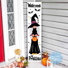 a welcome sign with a witch on it and pumpkins in front of the door