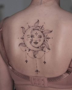 a woman's back with a sun and moon tattoo on it