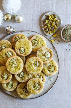 a plate full of cookies with nuts and pistachios on the table next to it