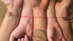 three people are holding their hands together with tattoos on them