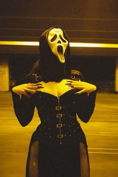 a woman in a black corset and mask with her hands on her hips