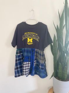 there is a shirt and plaid shorts hanging on the wall next to a potted plant