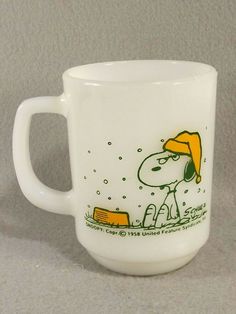 a white coffee cup with a snoopy cartoon on the side and yellow trimmings