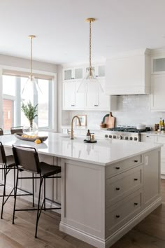 a large kitchen with white cabinets and an island in the middle is surrounded by bar stools