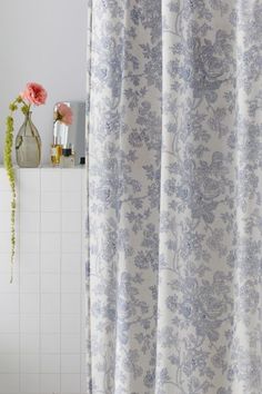 a shower curtain with blue and white flowers on it next to a bathtub in a bathroom