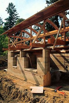 a house under construction with wooden beams and roof trusss on the side of it