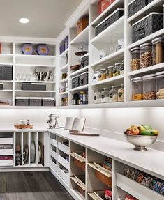 a kitchen with white cabinets and shelves filled with food