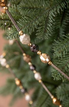 a close up of a christmas tree with ornaments on the branches and beads hanging from it