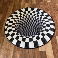 a black and white checkered area rug with a circular hole in the middle on a wooden floor