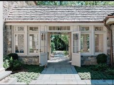 an open door leading into a stone house with white trim and windows on the side