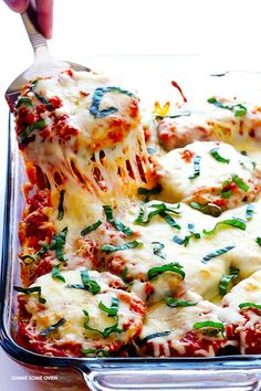 a casserole dish with cheese and spinach being lifted from the casserole