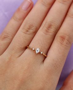 a woman's hand with a diamond ring on top of her left hand,