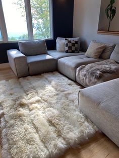 a living room with a large sectional couch and white sheepskin rug on the floor