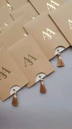 six business cards with tassels on top of each one and the letter a in gold foil