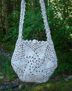 a white crocheted bag hanging from a tree