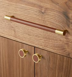 a wooden cabinet with brass handles and two round knobs on the door handle,