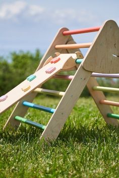 a wooden playground set in the grass with colorful sticks sticking out of it's sides