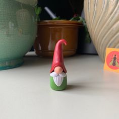 a gnome figurine sitting on top of a table next to potted plants