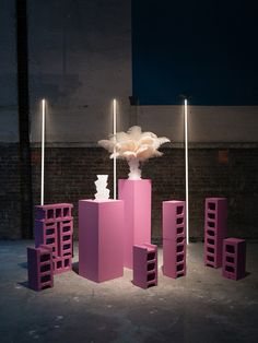 an arrangement of pink and purple boxes with lights on them in front of a brick wall