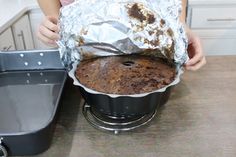 a person holding a cake in foil over a pan