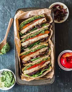 a pan filled with sandwiches and sauces on top of a table