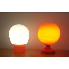 two different colored lamps sitting on top of a table