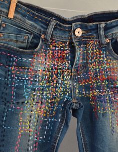 a pair of jeans with colorful stitching on them